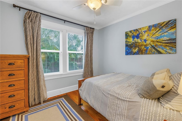 bedroom with a ceiling fan, crown molding, baseboards, and wood finished floors