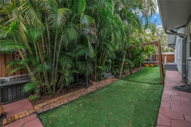 view of yard featuring a trampoline and fence