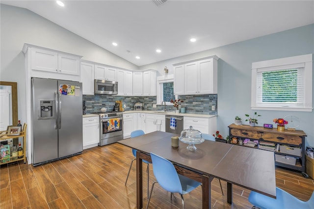 kitchen with stainless steel appliances, vaulted ceiling, light countertops, and a sink