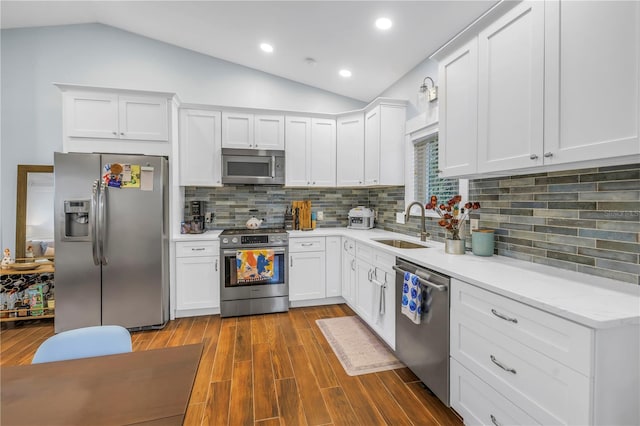 kitchen featuring white cabinets, vaulted ceiling, stainless steel appliances, and dark wood finished floors