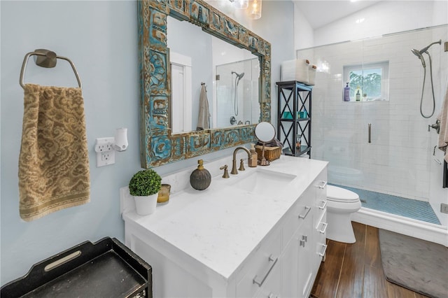 bathroom featuring a stall shower, toilet, lofted ceiling, wood finished floors, and vanity