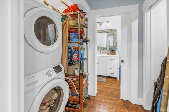 clothes washing area with laundry area, wood finished floors, and stacked washer and clothes dryer