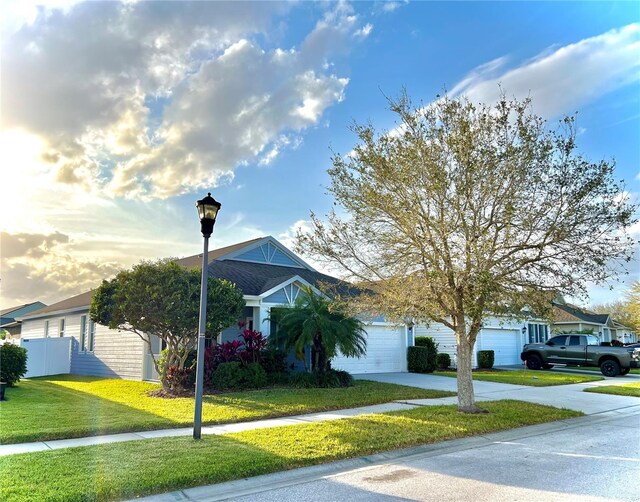 view of front of home featuring driveway, a front lawn, an attached garage, and fence