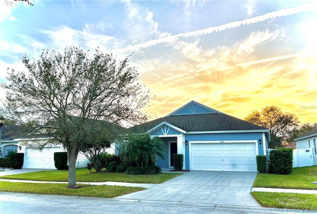 view of front of property featuring a garage, driveway, a shingled roof, and a lawn