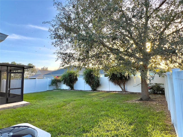 view of yard featuring a sunroom, a fenced backyard, and cooling unit