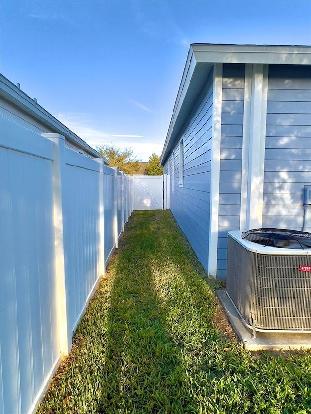 view of property exterior with a fenced backyard, a lawn, and central AC unit