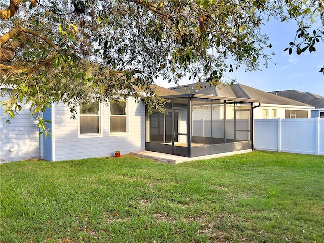 back of house with a lawn, fence, and a sunroom