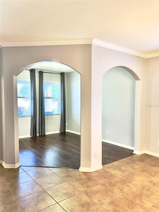 spare room with baseboards, arched walkways, and crown molding