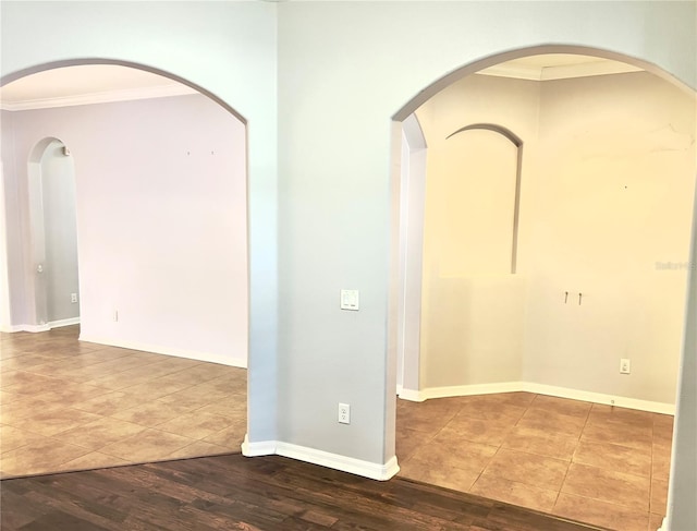 unfurnished room featuring baseboards, wood finished floors, and crown molding