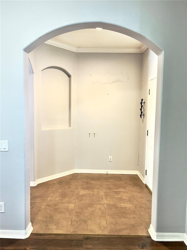 interior space featuring arched walkways, tile patterned flooring, crown molding, and baseboards