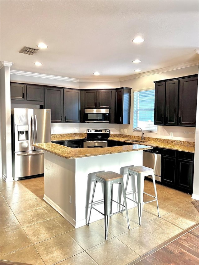 kitchen with stainless steel appliances, a breakfast bar, a sink, visible vents, and a center island