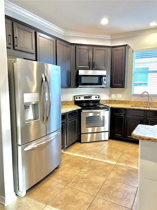 kitchen with light tile patterned floors, light stone counters, stainless steel appliances, a sink, and ornamental molding