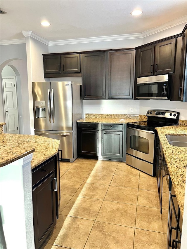 kitchen with stainless steel appliances, light tile patterned flooring, dark brown cabinetry, and crown molding