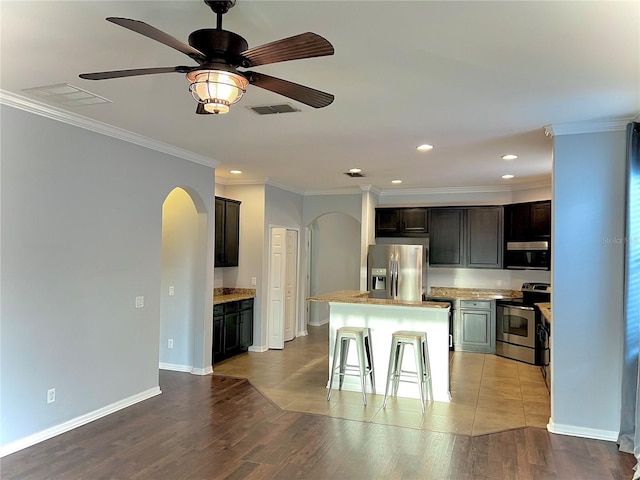 kitchen featuring visible vents, arched walkways, a kitchen island, appliances with stainless steel finishes, and wood finished floors