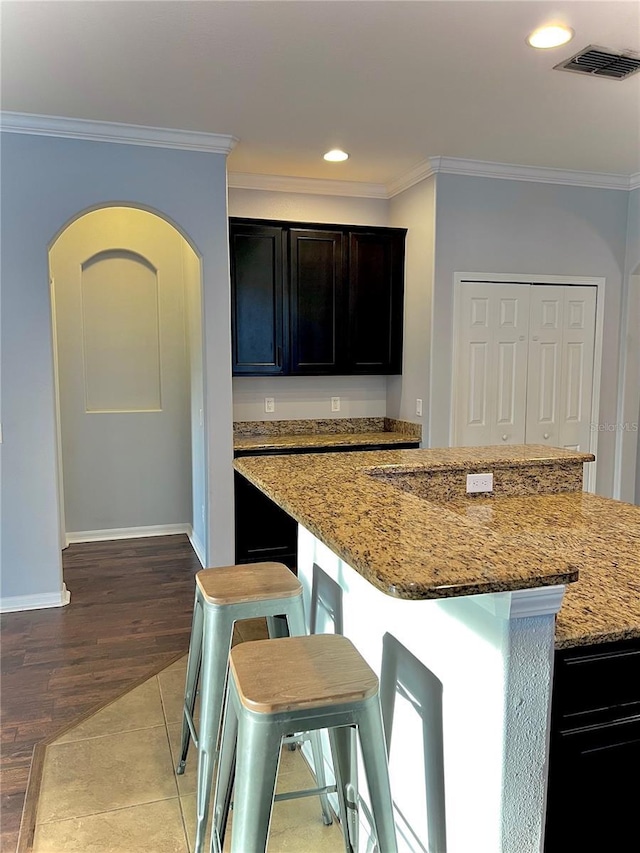 kitchen with light stone countertops, visible vents, and crown molding