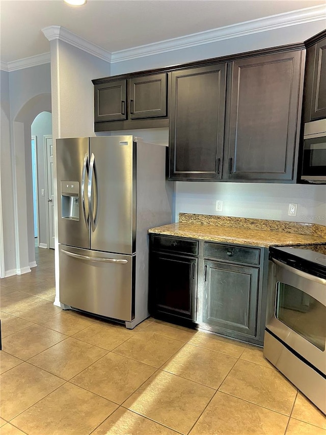 kitchen with arched walkways, crown molding, light tile patterned floors, appliances with stainless steel finishes, and light stone countertops