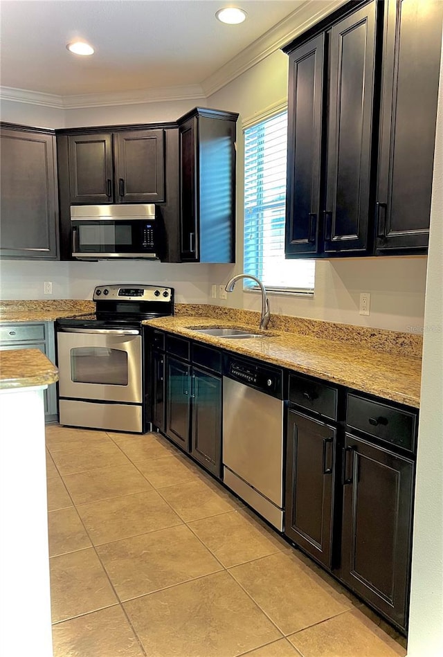 kitchen featuring appliances with stainless steel finishes, crown molding, a sink, and light tile patterned floors