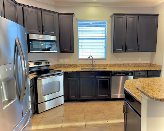 kitchen featuring light stone counters, crown molding, light tile patterned floors, appliances with stainless steel finishes, and a sink