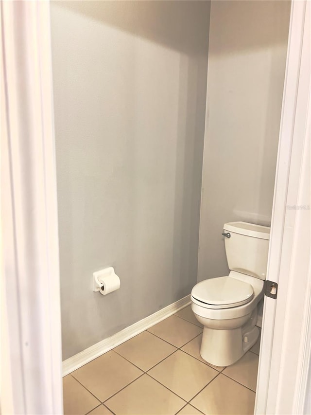 bathroom with baseboards, toilet, and tile patterned floors