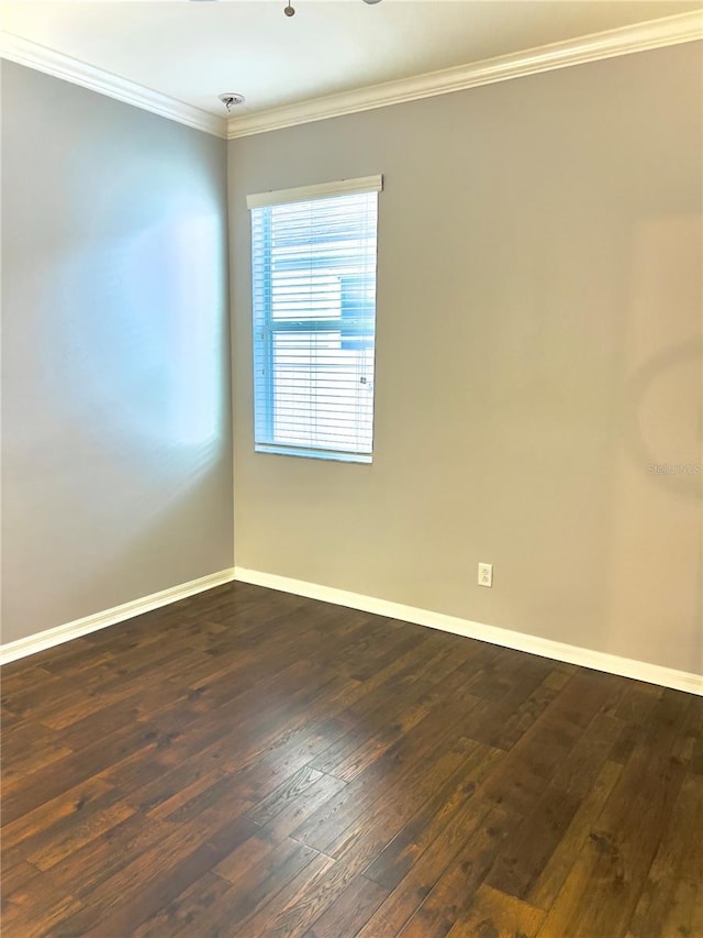 empty room with crown molding, dark wood finished floors, and baseboards