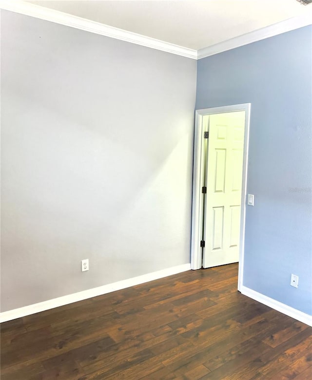 spare room with dark wood-style flooring, crown molding, and baseboards