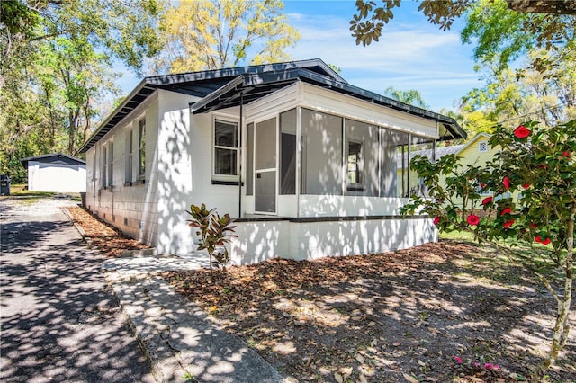 view of property exterior featuring concrete block siding and a sunroom