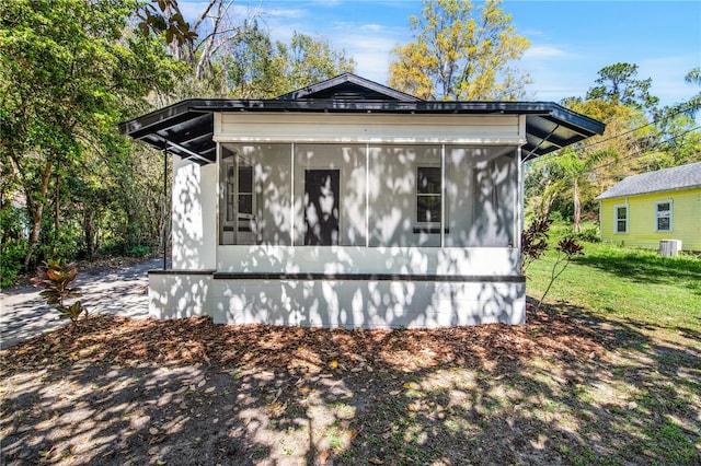 view of side of property featuring a yard, central AC, and a sunroom