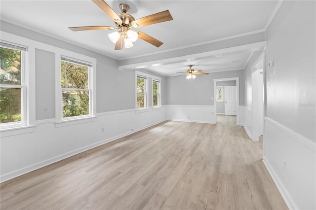 spare room featuring baseboards, a wainscoted wall, light wood finished floors, and ornamental molding