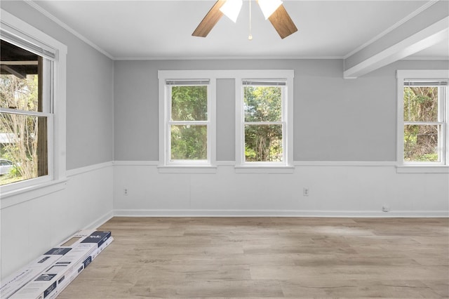 unfurnished room featuring light wood finished floors, wainscoting, crown molding, and ceiling fan