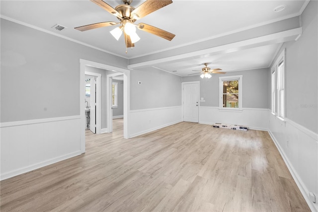 spare room featuring crown molding, light wood-style floors, a wainscoted wall, and ceiling fan