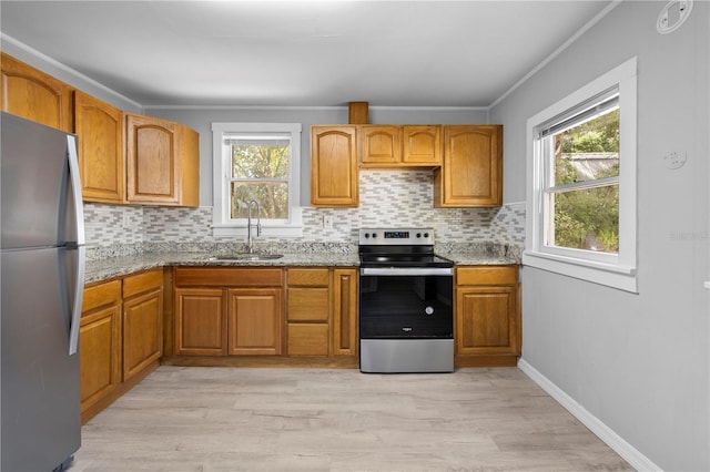 kitchen featuring a sink, stainless steel appliances, light stone countertops, and a healthy amount of sunlight