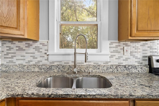 kitchen featuring a sink, light stone counters, and tasteful backsplash