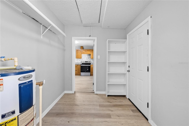 spacious closet featuring water heater, light wood-style flooring, and attic access