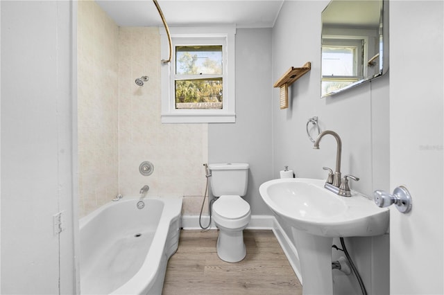 bathroom featuring washtub / shower combination, toilet, wood finished floors, and baseboards