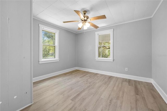 empty room with light wood-type flooring, plenty of natural light, baseboards, and ornamental molding