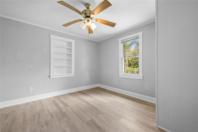 spare room with built in features, wood finished floors, baseboards, and ornamental molding