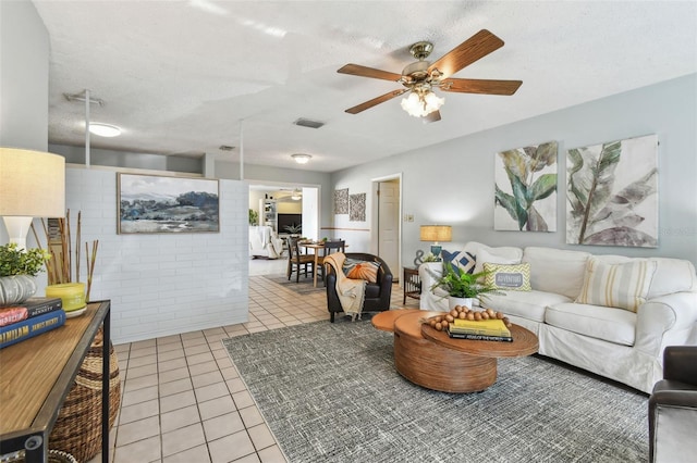 tiled living area with a ceiling fan, visible vents, and a textured ceiling