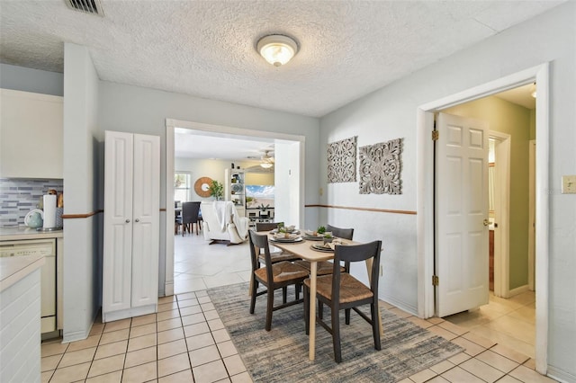 dining room with light tile patterned floors, visible vents, and a textured ceiling