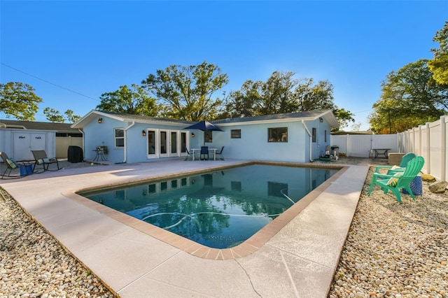 rear view of house with a patio, a fenced in pool, a fenced backyard, stucco siding, and french doors