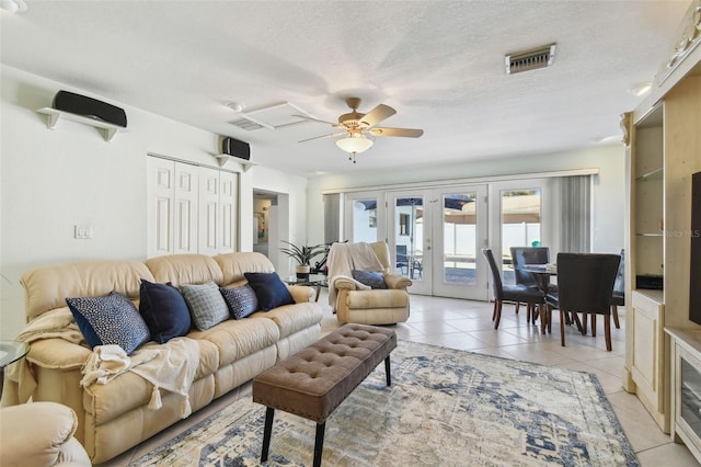 living room with light tile patterned floors, a ceiling fan, visible vents, french doors, and a textured ceiling