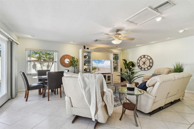 living room with light tile patterned floors, visible vents, a textured ceiling, and attic access