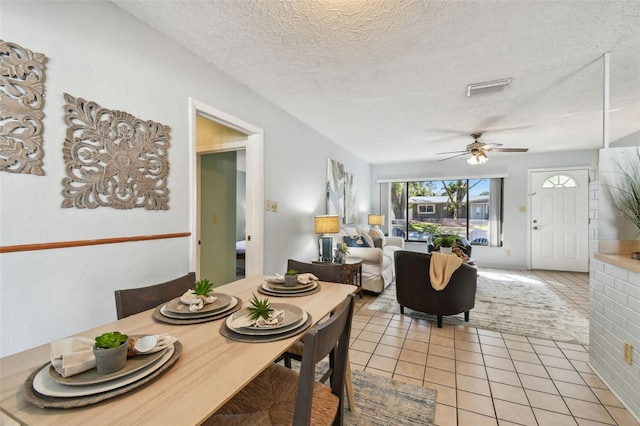 dining room featuring light tile patterned floors, a ceiling fan, visible vents, and a textured ceiling