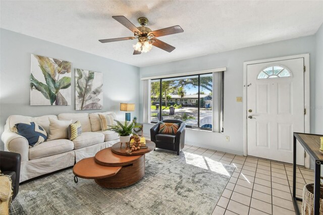 living area with light tile patterned floors, baseboards, a textured ceiling, and ceiling fan