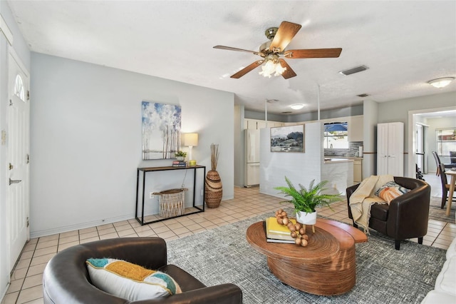 living area featuring light tile patterned flooring, baseboards, visible vents, and ceiling fan