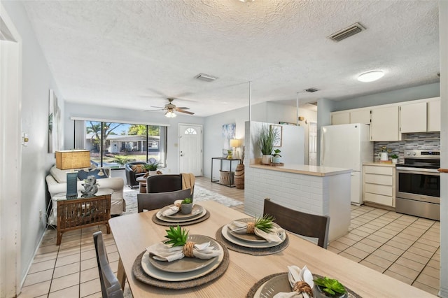 dining room featuring visible vents, a textured ceiling, light tile patterned flooring, and a ceiling fan