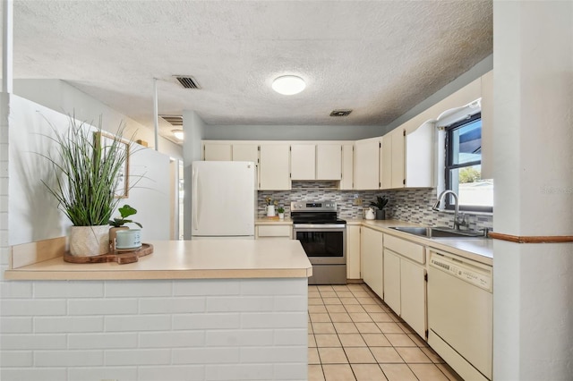 kitchen featuring white appliances, visible vents, a peninsula, a sink, and tasteful backsplash