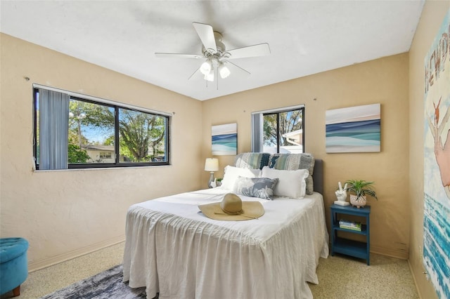 bedroom with speckled floor, baseboards, and a ceiling fan