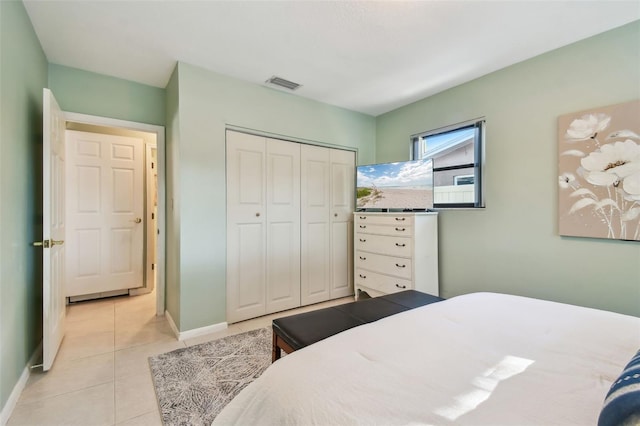 bedroom featuring light tile patterned floors, visible vents, baseboards, and a closet