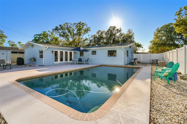 back of property featuring a patio, a fenced in pool, a fenced backyard, stucco siding, and french doors