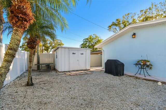 view of yard with an outdoor structure, a fenced backyard, and a shed